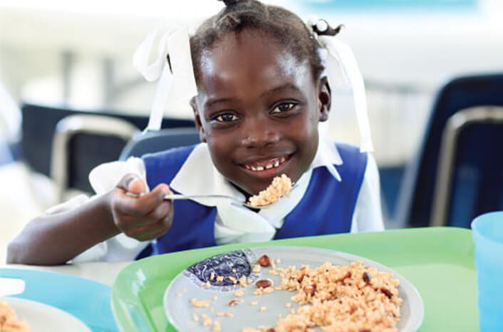 A hungry young girl eating eggs