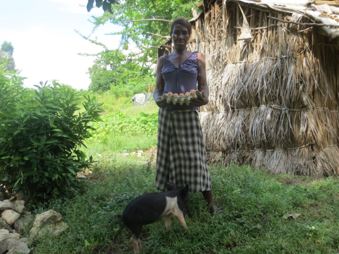 Angel poses with a fresh crate of eggs and the pig she was able purchase thanks to the success of her chicken farm project.