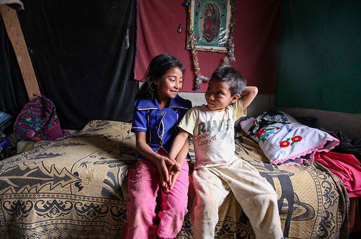 two impoverished children sitting on a bed