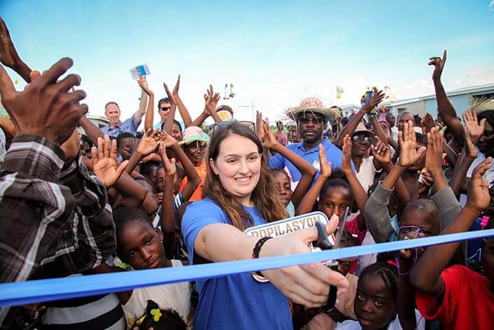 a volunteer cutting the ribbon at the opening of a care facility 